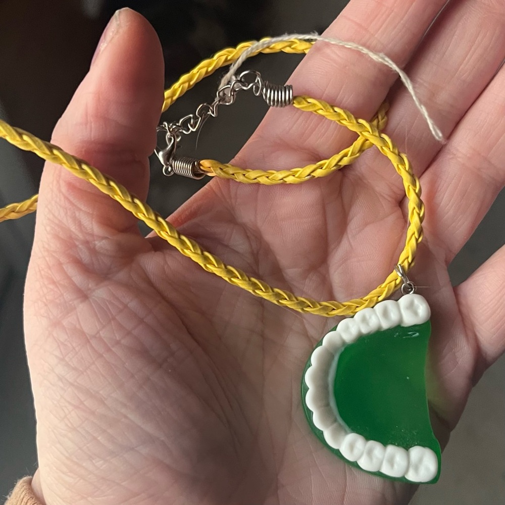 Green and white resin tooth necklace with yellow cord